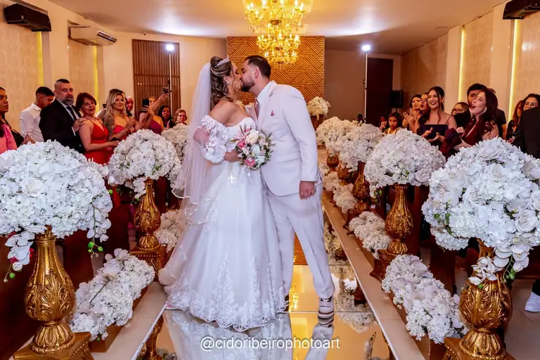 Beijo dos noivos na capela do Espaço Montello com decoração de flores brancas